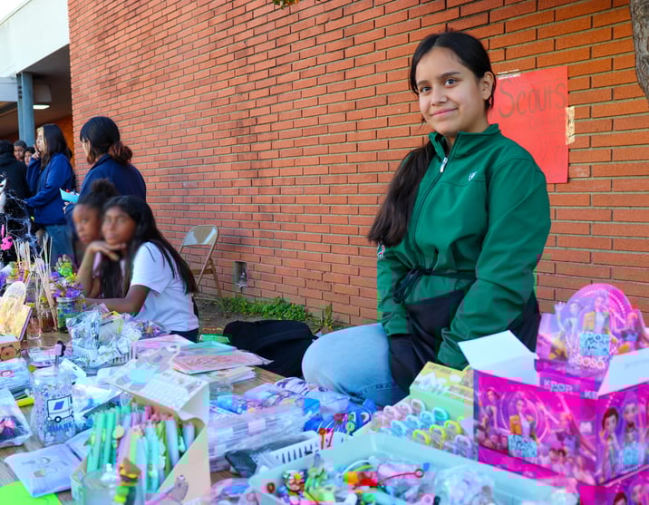 Alma Fuerte Business Fair - Image featuring Katia seated at a table displaying various crafts and K-pop merchandise.