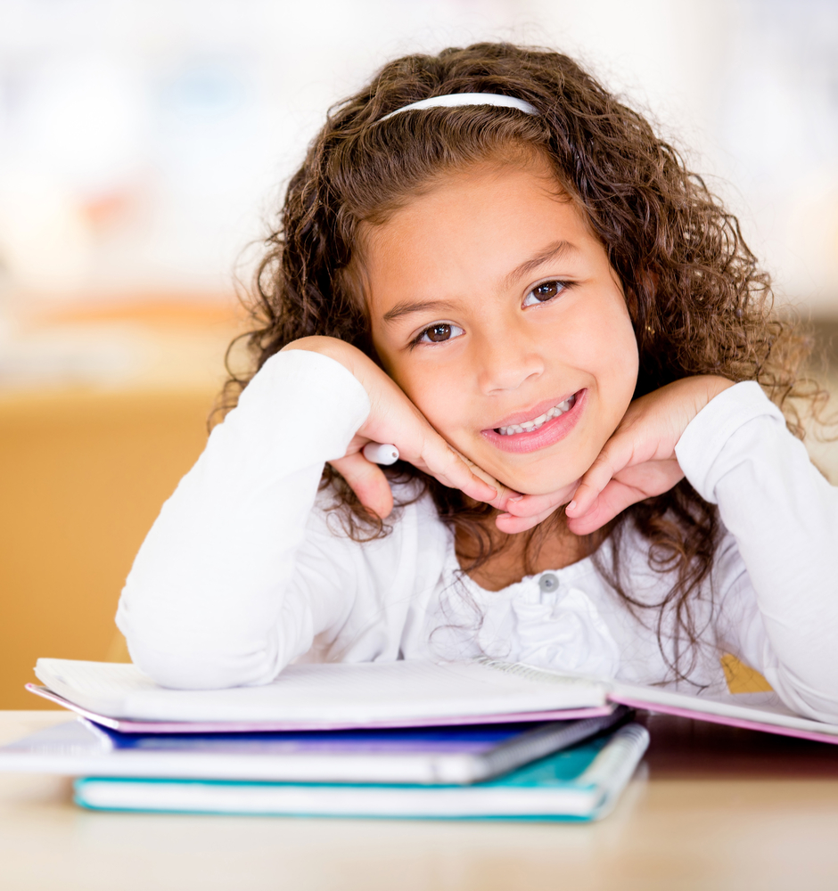 Cute school girl doing her homework and looking happy