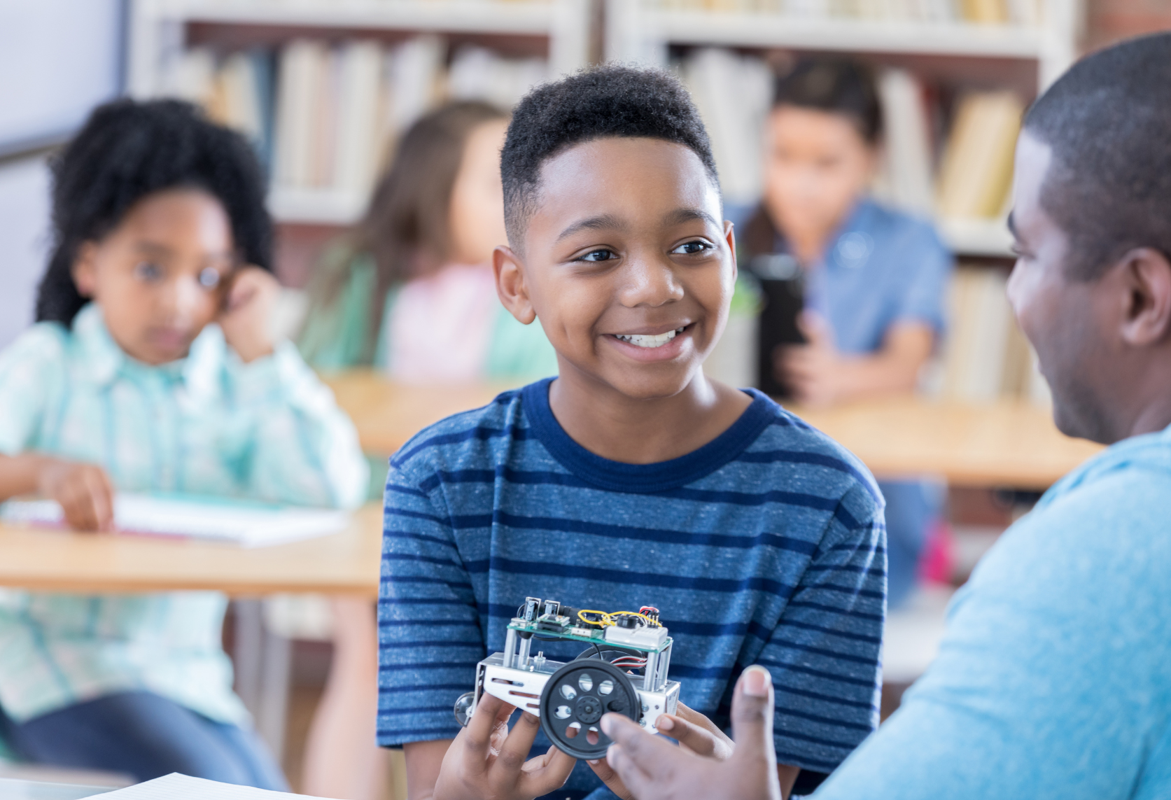 Middle school student at robotics club happening in a shared space, the library. 